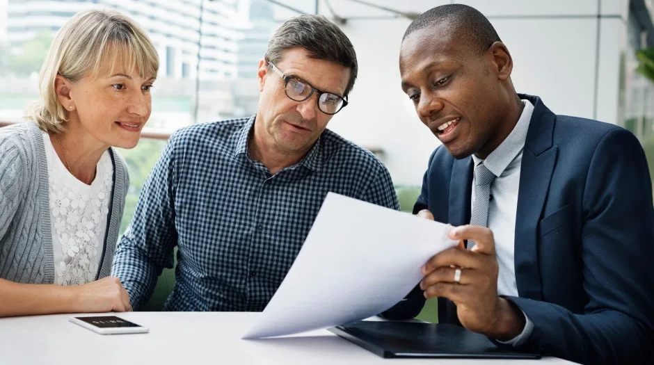An agent walking a couple through their plan at the table
